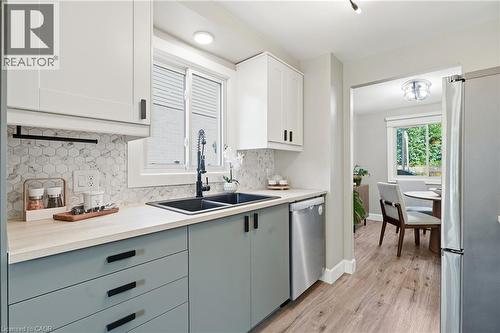 Kitchen featuring two-tone cabinetry, hexagon tile backsplash, and wood-finish flooring - 563 Westvale Drive, Waterloo, ON - Indoor Photo Showing Kitchen With Double Sink With Upgraded Kitchen