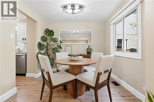 Wood-finish flooring, recessed lighting, white trim, and a built-in kitchen featuring white cabinetry and stainless steel appliances - 563 Westvale Drive, Waterloo, ON - Indoor Photo Showing Dining Room
