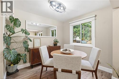Recessed lighting with a contemporary ceiling fixture, wood-finish flooring, and a large window - 563 Westvale Drive, Waterloo, ON - Indoor Photo Showing Dining Room