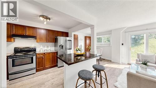 Open-concept kitchen featuring wood cabinetry, stainless steel appliances, and a breakfast bar - 304 Bluevale Street N, Waterloo, ON - Indoor Photo Showing Kitchen
