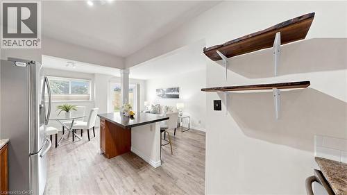 Wood-finish flooring, stainless steel refrigerator, kitchen island with dark countertop, and decorative wall shelving - 304 Bluevale Street N, Waterloo, ON - Indoor