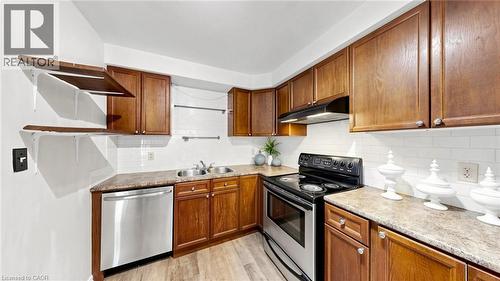 Kitchen featuring wood-finish cabinetry, stainless steel dishwasher, double basin sink, electric range, and wood-finish flooring - 304 Bluevale Street N, Waterloo, ON - Indoor Photo Showing Kitchen With Double Sink
