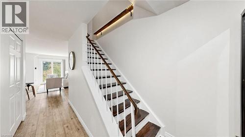 Hardwood flooring throughout, white painted walls, white trim, and a staircase with dark wood treads and a wood handrail - 304 Bluevale Street N, Waterloo, ON - Indoor Photo Showing Other Room