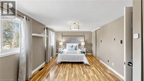 Hardwood flooring, multiple windows, built-in shelving, sliding closet doors, and a ceiling-mounted light fixture - 304 Bluevale Street N, Waterloo, ON - Indoor Photo Showing Bedroom