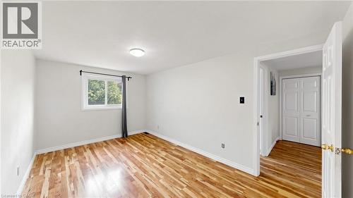 Wood-finish flooring, white walls, flush mount lighting, single window, and a white interior door - 304 Bluevale Street N, Waterloo, ON - Indoor Photo Showing Other Room