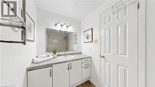White paneled cabinetry with modern hardware, a countertop with an integrated sink, a rectangular mirror, and a four-light vanity fixture - 304 Bluevale Street N, Waterloo, ON - Indoor Photo Showing Bathroom