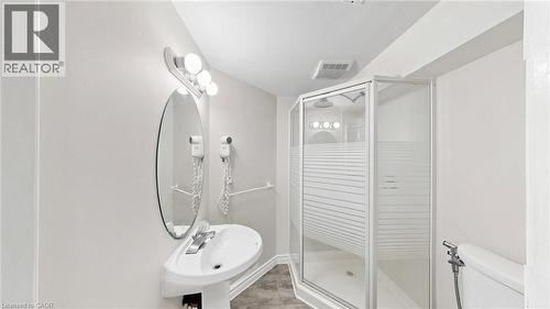 Pedestal sink with chrome faucet, oval wall mirror, and vanity lighting - 304 Bluevale Street N, Waterloo, ON - Indoor Photo Showing Bathroom