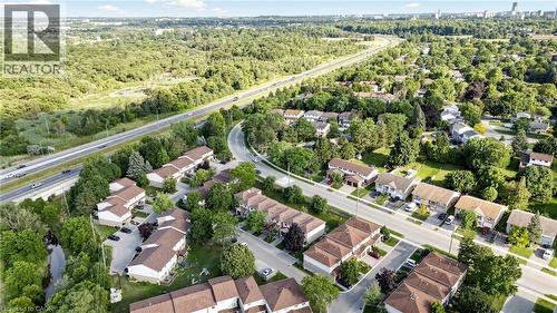 Aerial perspective showcasing a developed residential area with multiple housing units, proximity to a multi-lane roadway, and extensive surrounding tree coverage - 304 Bluevale Street N, Waterloo, ON - Outdoor With View