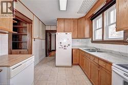 Kitchen featuring wood cabinetry, a dual basin sink, and tile flooring - 