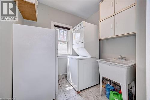 Laundry area featuring a utility sink, wall-mounted cabinetry, a window, and tile flooring - 147 Courtland Avenue E, Kitchener, ON - Indoor Photo Showing Laundry Room