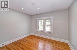 Hardwood flooring room featuring white baseboards, light gray walls, and a multi-pane window with white trim - 