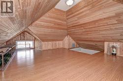 Expansive loft area featuring wood-finish flooring, wood plank walls, and a vaulted wood plank ceiling - 