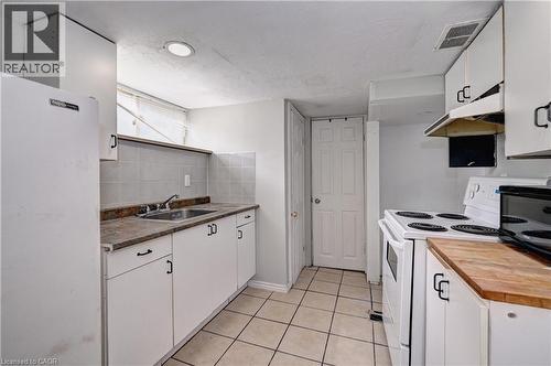 Kitchen featuring white cabinetry with dark hardware, a stainless steel sink, and a white refrigerator - 147 Courtland Avenue E, Kitchener, ON - Indoor Photo Showing Kitchen