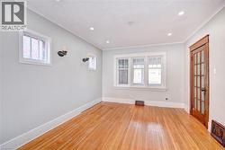 Hardwood flooring extends throughout the room, complemented by recessed ceiling lights and wall sconces - 