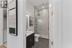 Bathroom featuring a dark wood vanity with white countertop, circular mosaic floor tiles, a frameless glass shower enclosure, and brass fixtures - 