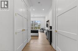 Hardwood-finish flooring, recessed lighting, white paneled doors with gold-tone hardware, and a large window with exterior scenery - 