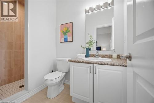 Shower with tiled walls, white toilet, single vanity with a built-in sink, stone-finish countertop, and white cabinetry - 20 Todd Crescent, Dundalk, ON - Indoor Photo Showing Bathroom