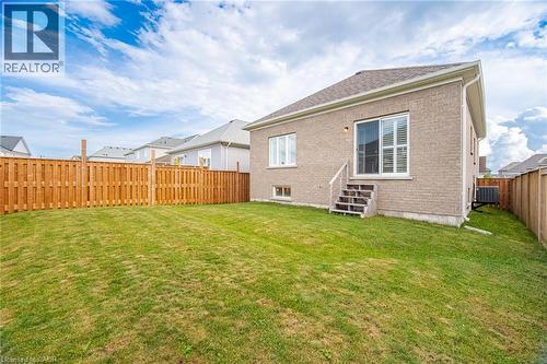 Spacious backyard featuring a manicured lawn, wood-finish privacy fencing, and brick exterior with modern architectural detailing - 20 Todd Crescent, Dundalk, ON - Outdoor