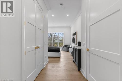 Hardwood-finish flooring, recessed lighting, white paneled doors with gold-tone hardware, and a large window with exterior scenery - 2 Arbourvale Common Unit# 209, St. Catharines, ON - Indoor Photo Showing Other Room