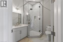 Bathroom featuring a vanity with an integrated sink, a glass-enclosed shower, a built-in shower niche, and wall-mounted light fixtures - 