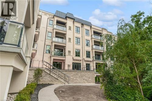 Multi-story building with a light-colored facade, featuring multiple balconies with glass railings - 2 Arbourvale Common Unit# 209, St. Catharines, ON - Outdoor With Balcony