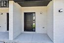 Contemporary entry featuring a black paneled door with sidelight, white painted brick facade, concrete porch, and black outdoor sconces - 45B Howard Street, Hagersville, ON 
