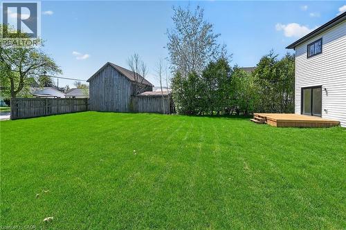 Expansive green lawn with a newly constructed wooden deck featuring steps and a sliding glass door entry to the home - 45B Howard Street, Hagersville, ON 