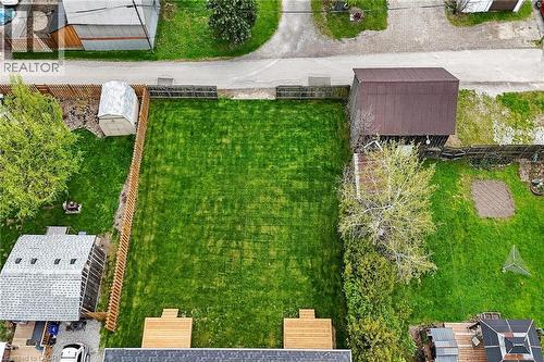 Expansive fenced yard featuring a manicured lawn, two distinct wood decks, and mature perimeter trees - 45B Howard Street, Hagersville, ON 