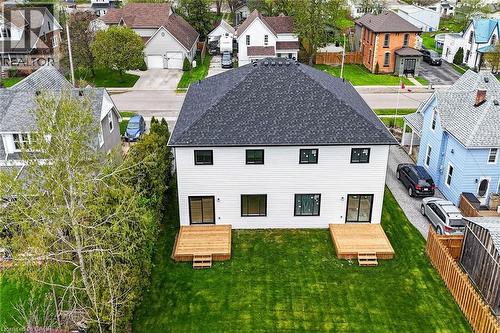 Rear exterior featuring white horizontal siding, a dark shingle roof, and a manicured green lawn - 45B Howard Street, Hagersville, ON 
