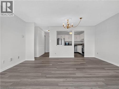 Wood-finish flooring throughout, crown molding detailing, and a chandelier with ceiling medallion - 7 Gale Crescent Unit# 1107, St. Catharines, ON 