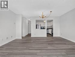 Wood-finish flooring throughout, crown molding detailing, and a chandelier with ceiling medallion - 