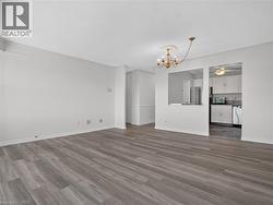 Wood-finish flooring throughout, crown molding detail, recessed wall cut-out, and a kitchen featuring white cabinetry and appliances - 