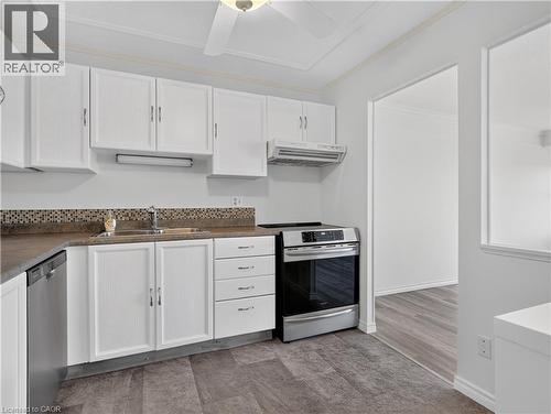 Kitchen featuring white cabinetry, mosaic tile backsplash, wood-finish flooring, stainless steel dishwasher, and stainless steel range - 7 Gale Crescent Unit# 1107, St. Catharines, ON 