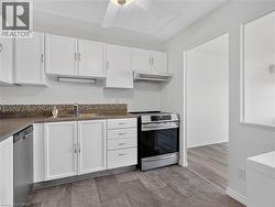 Kitchen featuring white cabinetry, mosaic tile backsplash, wood-finish flooring, stainless steel dishwasher, and stainless steel range - 