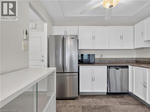 Kitchen featuring white cabinetry, stainless steel appliances, mosaic tile backsplash, and a ceiling fan with integrated lighting - 7 Gale Crescent Unit# 1107, St. Catharines, ON 