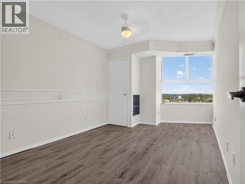 Light-toned walls with decorative molding, large window, wood-finish flooring, and ceiling fan - 7 Gale Crescent Unit# 1107, St. Catharines, ON 