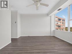 Expansive window wall, wood-finish flooring, ceiling fan, crown molding, and bright white walls - 