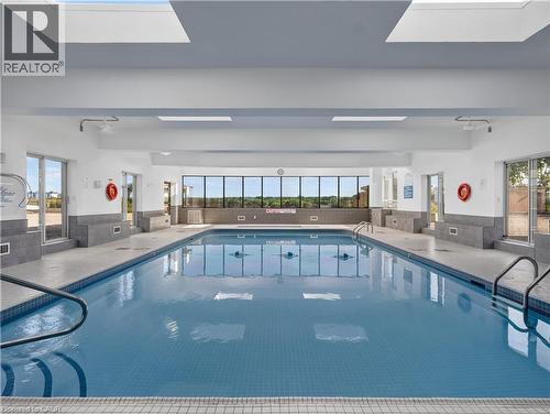 Indoor swimming pool with blue mosaic tile, multiple skylights, and expansive exterior-facing windows - 7 Gale Crescent Unit# 1107, St. Catharines, ON 