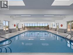 Indoor swimming pool with blue mosaic tile, multiple skylights, and expansive exterior-facing windows - 