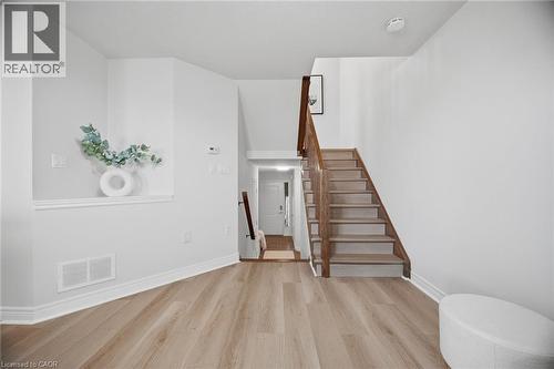 Wood-finish flooring throughout, solid wood staircase with wood handrail, and crisp white wall finishes - 98 Bloom Crescent, Stoney Creek, ON 