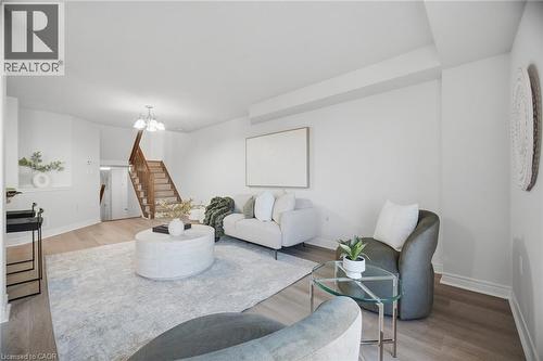 Hardwood-style flooring throughout, white painted walls, and an exposed wood staircase with natural finish - 98 Bloom Crescent, Stoney Creek, ON 