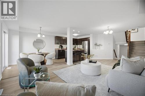 Open-concept living area featuring wood-finish flooring, recessed lighting, and a modern chandelier - 98 Bloom Crescent, Stoney Creek, ON 