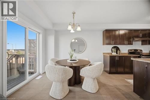 Sliding glass doors, wood-finish flooring, dark wood cabinetry, white subway tile backsplash, and a built-in electric range - 98 Bloom Crescent, Stoney Creek, ON 