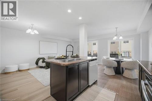 Open-concept layout featuring wood-finish flooring, recessed lighting, and a kitchen island with an undermount double-basin sink - 98 Bloom Crescent, Stoney Creek, ON 