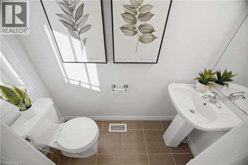 White pedestal sink with chrome faucet, white toilet, and tiled flooring - 98 Bloom Crescent, Stoney Creek, ON 