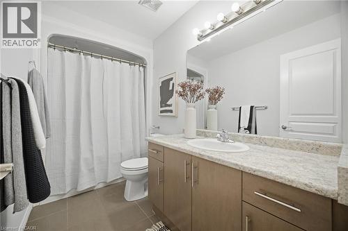Bathroom featuring a vanity with an integrated sink, broad mirror, and a shower-tub combination - 98 Bloom Crescent, Stoney Creek, ON 