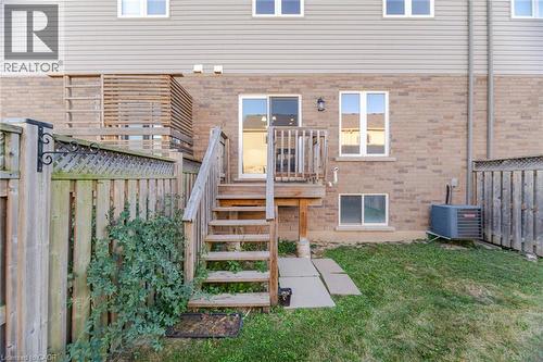 Brick and siding exterior featuring a wooden deck with stairs, a sliding glass door, and a ground-level window - 98 Bloom Crescent, Stoney Creek, ON 