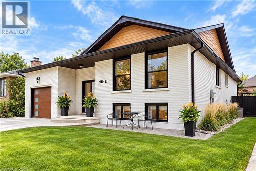 White brick exterior with black framed windows, wood-finish garage door, and a stone entryway - 9 Midway Street, Hamilton, ON 
