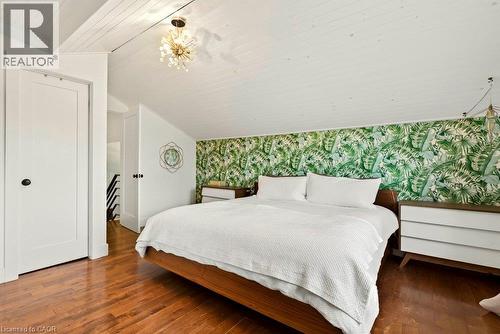 Wood-finish flooring, white paneled door, sloped white paneled ceiling, and a decorative ceiling light fixture - 9 Midway Street, Hamilton, ON 