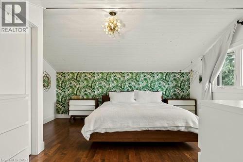 Hardwood flooring, sloped white paneled ceiling, decorative light fixture, accent wall with botanical pattern, and an operable window - 9 Midway Street, Hamilton, ON 